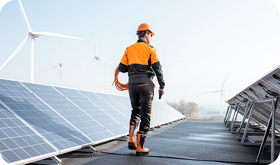 Man wearing an orange helmet working next to solar panels.